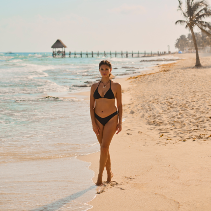 A woman on the beach wearing a black bikini